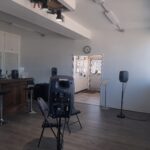 Chairs and Small loudspeakers on stands in a gallery.