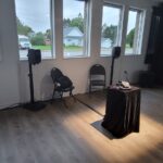 Rotary Telephone on a black podium with windows, chairs and loudspeakers.